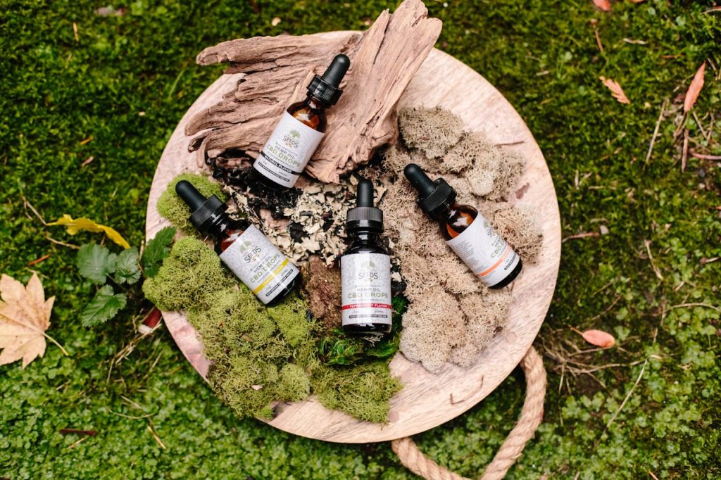 Crafting Captivating Headlines: Your awesome post title goes here Natural CBD oil bottles with droppers on a wooden board surrounded by moss and leaves.